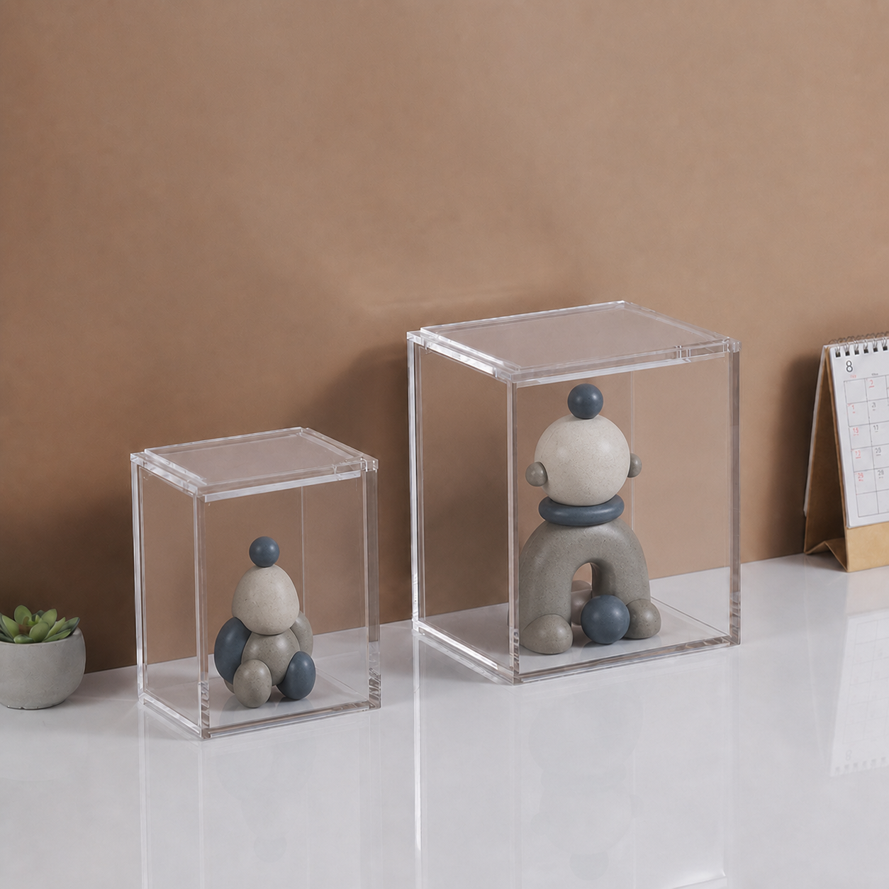 Two clear acrylic figure display cases containing original unbranded sculptural figures